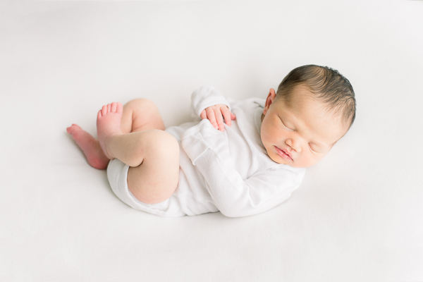 bright and airy newborn image with baby on white blanket in Houston studio