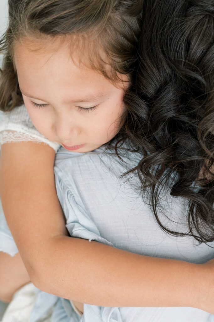 A young girl hugs her mom wearing a blue dress after shopping at Threadfare