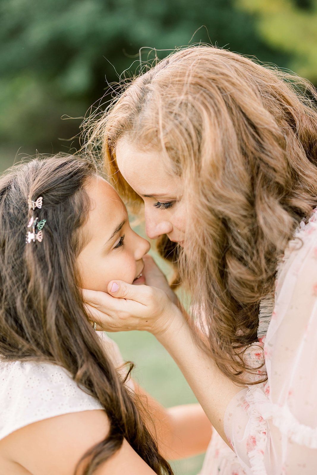 A mother cradles her toddler daughters head while playing in a park