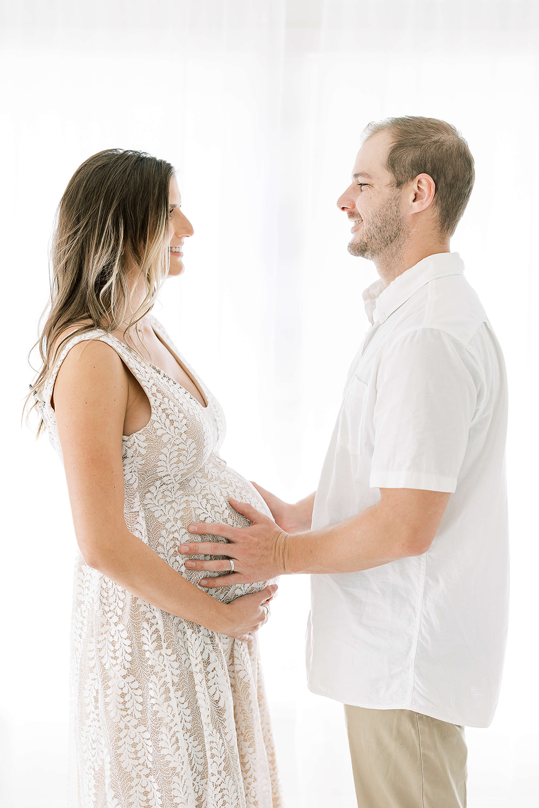 Happy new parents hold the bump while standing in a studio before some Houston Prenatal Yoga