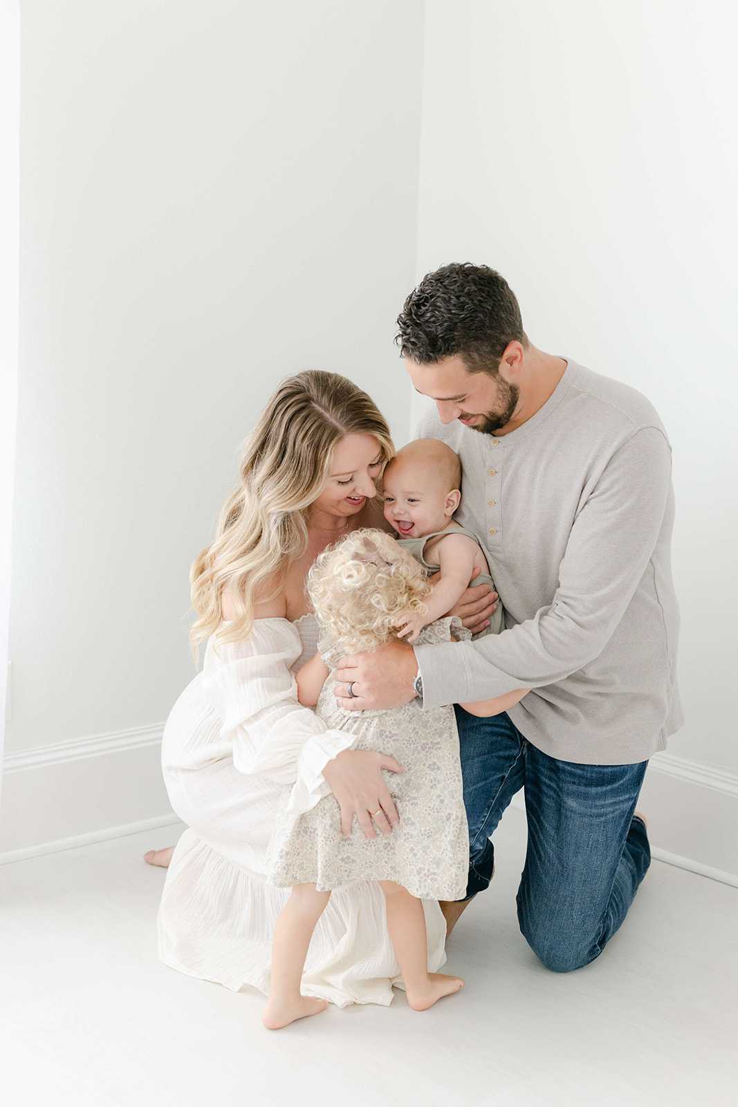 AA happy family of 4 play together in a studio before some Infant Swim Lessons Houston