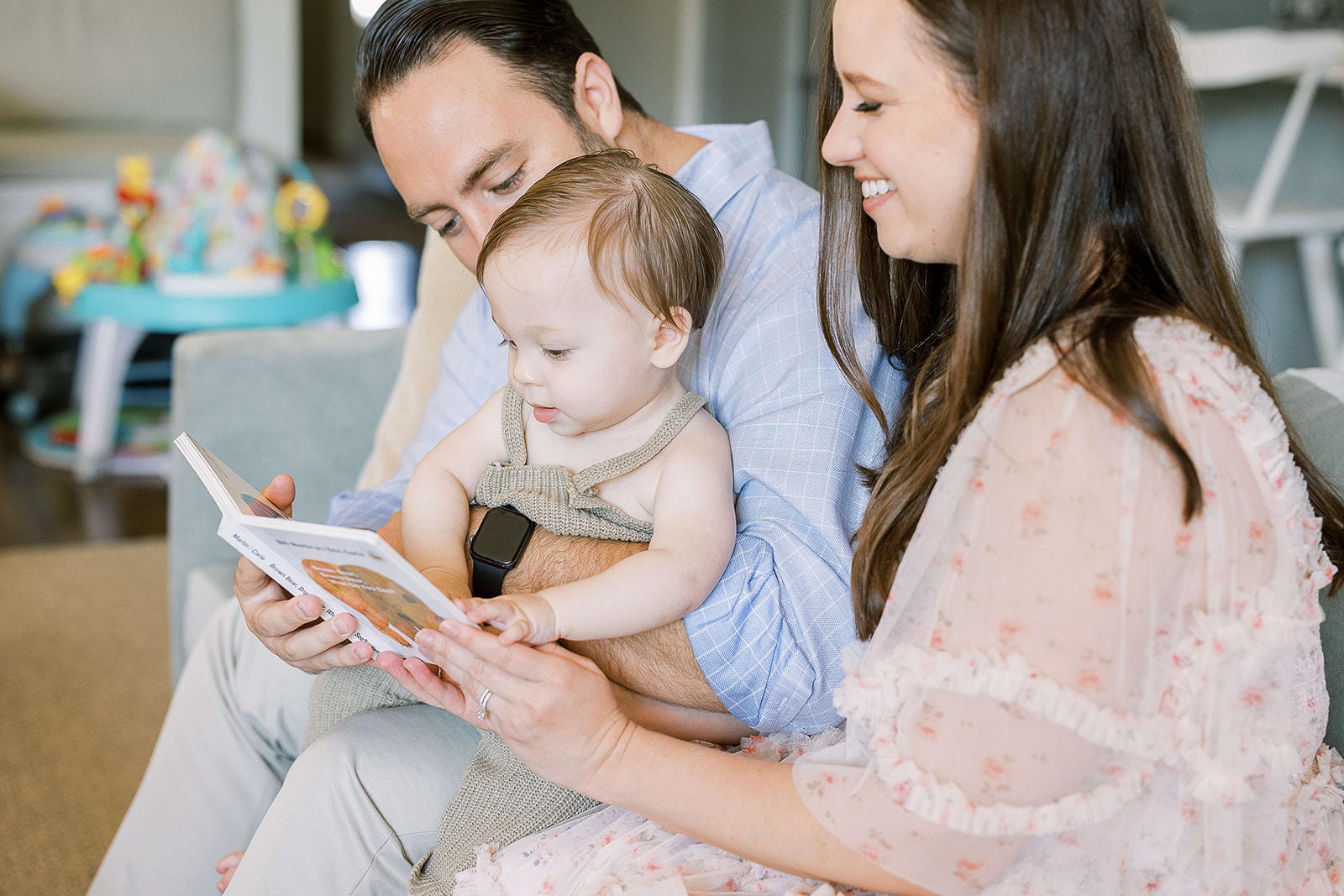 Happy mom and dad read a book with their toddler son in their laps after some great Parenting Classes Houston