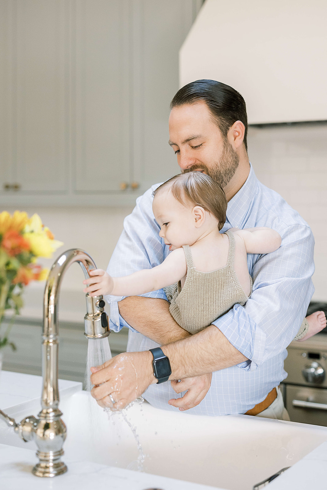 A father plays in a sink with his toddler in his arms after some Parenting Classes Houston